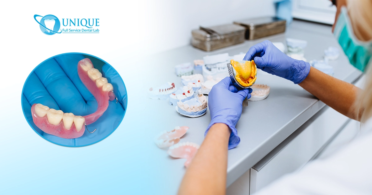 A dental professional in a laboratory fabricating custom partial dentures, holding an impression tray among various dental casting models.